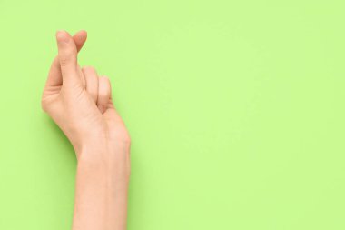 Yeşil arka planda kalp hareketi gösteren bir kadın el.