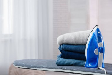 Temiz kıyafetler ve elektrikli ütü odada.