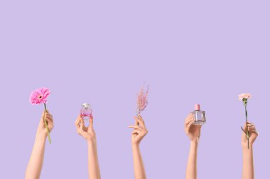 Kadın eli, parfüm şişeleri ve leylak arkaplanda çiçekler.