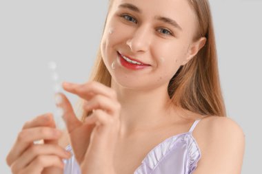 Sivilceli ve sivilceli genç bir kadın arka planda gülümsüyor, yakın plan.