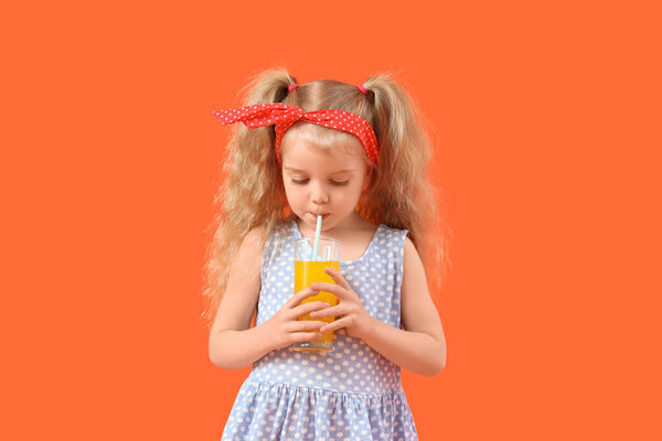 Красивая маленькая девочка пьет апельсиновый сок на цветном фоне