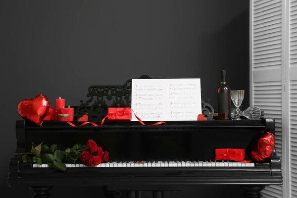 Piano with note sheets and decor for Valentine's Day near dark wall in room