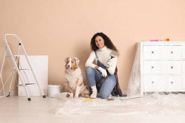 Fırçalı mutlu kadın Afro-Amerikan ressam ve yeni evdeki tamirat sırasında Avustralya çoban köpeği boyama duvarı.