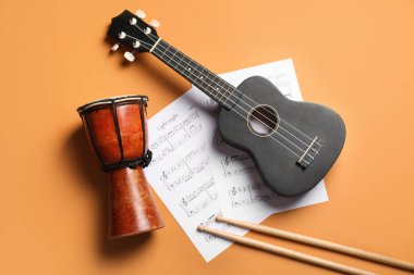 Renk arkaplanında Ukulele, davul, sopa ve müzik sayfaları