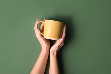 Yeşil arka planda sarı kupalı kadın elleri