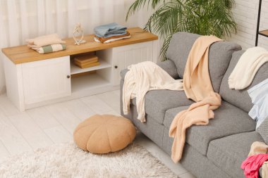 Gri kanepesi, tuvaleti ve dağınık giysileri olan dağınık bir oturma odası.