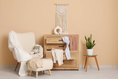 Koltuğu, dağınık giysileri ve bej duvarın yanındaki tuvaleti olan dağınık bir oturma odası.