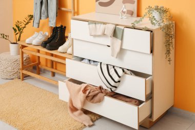 Klozet dağınık kıyafetler ve ayakkabılar oturma odasındaki sarı duvarın yanında, yakın plan.