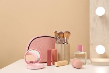 Bej duvarın yanındaki masada makyaj malzemeleri olan makyaj çantası, yakın plan.