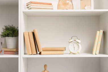 Kitaplı raflar, saat ve şık dekorlar, yakın plan.