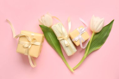 Pembe arka planda hediye kutuları ve lale çiçekleri olan kompozisyon