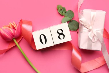 Küp takvim, lale çiçeği, kurdele ve Uluslararası Kadınlar Günü kutlamaları için pembe arka planda hediye paketi