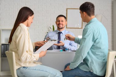 Ofiste çiftlerle çalışan bir emlakçı.