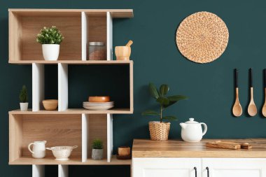 Mutfağın içinde raf ünitesi ve mavi duvarın yanındaki masa.