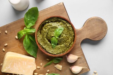 Tahta tahta tahtada lezzetli pesto sosu ve beyaz arka planda malzemeler var.