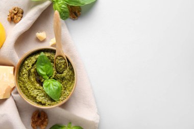 Tahta kaşık, ceviz, peynir ve fesleğen yapraklı bir kase lezzetli pesto sosu.