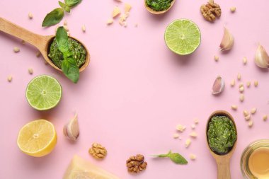 Lezzetli pesto soslu ahşap kaşıklardan yapılmış çerçeve ve pembe arka planda malzemeler