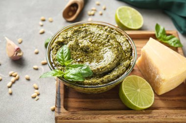 Ahşap tahta tahtada lezzetli pesto sosu ve gri grunge arka planda malzemeler var.
