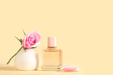 Bir şişe parfüm ve sarı arka planda güzel güllü dekoratif podyum.