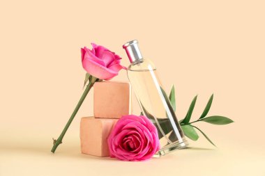 Parfüm şişesiyle dekoratif podyumlar ve sarı arka planda güzel pembe güller.