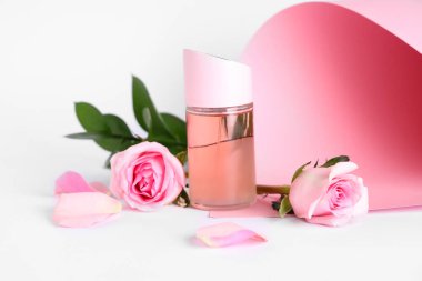 Renkli arka planda güzel pembe gülleri ve yaprakları olan bir şişe parfüm.