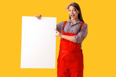 Genç bayan ressam sarı arkaplandaki boş postere bakıyor.