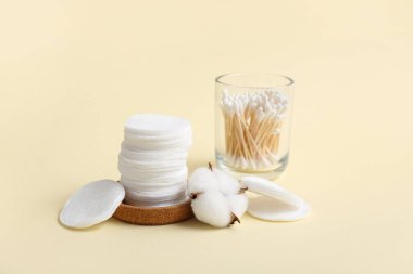 Renkli arka planda kozmetik pedler, pamuklar ve pamuk çiçekleri yığını