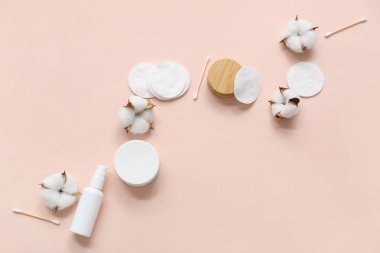 Renkli arka planda kozmetik ürünleri, yastıklar ve pamuk çiçekleriyle kompozisyon