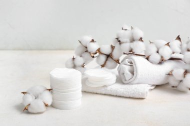 Kozmetik pedler, temiz havlular ve ışık masasında pamuk dalı.