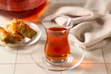 Beyaz fayanslı lezzetli baklavalı bir bardak Türk çayı.