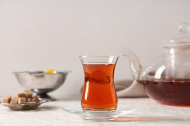 Beyaz zemin üzerinde şeker küpleri ve çaydanlık ile bir bardak Türk çayı