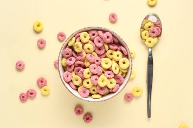 Bej arkaplanda mısır gevreği halkaları olan bir kase