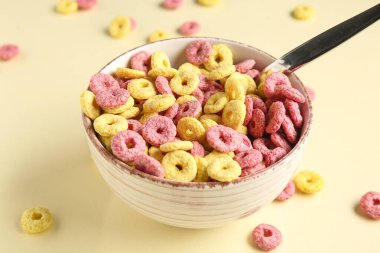 Bej arka planda mısır gevreği halkaları olan kase, yakın plan.