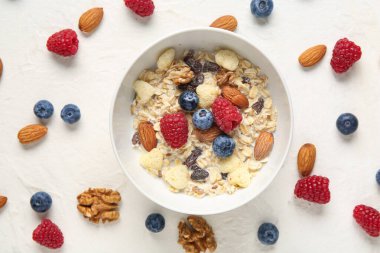 Beyaz arka planda mısır gevreği, fındık ve böğürtlen kâsesi