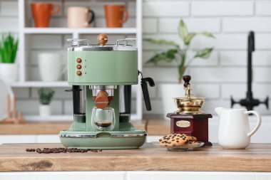 Modern kahve makinesi, bir bardak sıcak espresso ve mutfak tezgahında bir tabak tatlı kurabiye.