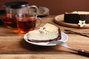 Bir parça vanilyalı cheesecake ve ahşap masada bir bardak çay.