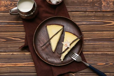 Tabakta vanilyalı cheesecake ve tahtadan arka planda bir sürahi süt
