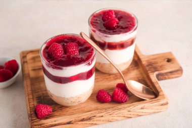 Beyaz arka planda lezzetli ahududulu cheesecake bardakları