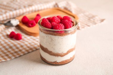 Bej arka planda lezzetli ahududulu cheesecake bardağı
