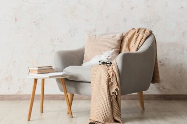 Oturma odasındaki ışık duvarının yanındaki koltukta yatan sevimli beyaz kedi.