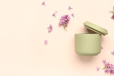 Banyo aksesuarları için kavanoz, bej arka planda leylak çiçekleri.