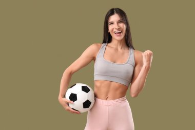Arka planda futbol topu olan mutlu, genç bir bayan.