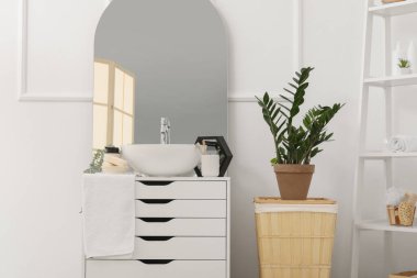 Lavabo, ayna ve banyo aksesuarları banyodaki çekmecelerin üzerinde.