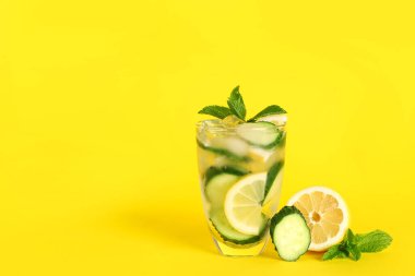 Bir bardak salatalıklı limonata ve sarı arka planda nane şekeri.