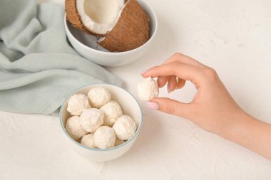 Kadın beyaz masada kaseden hindistan cevizi şekeri alıyor.