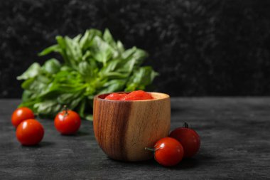 Arka planda bir kase konserve domates ve fesleğen.