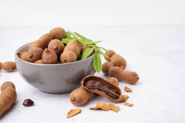 Bir kase lezzetli tamarind ve beyaz arka planda yaprak