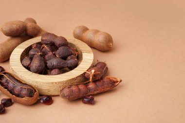 Bowl of tasty tamarinds and seeds on brown background clipart