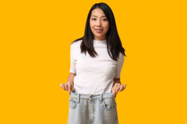 Sarı arka planda bol kotlu güzel, mutlu Asyalı kadın.