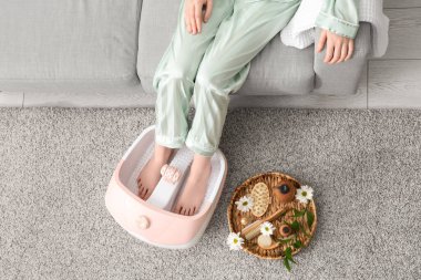 Kaplıca malzemeleri taşıyan bir kadın evde ayak banyosu yapıyor.